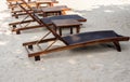 Empty adjustable wooden sunbeds with nobody decoration on sandy beach under the tree on sunny day.. Royalty Free Stock Photo