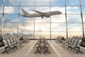 Empty airport terminal lounge with airplane on background.