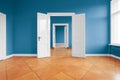 Empty apartment room with blue walls and parquet floor