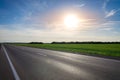 Empty asphalt highway against the bright sun at sunset