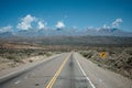 Empty highway with yellow line and traffic arrow sign in a desert valley in Andes Mountains -