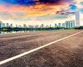 Empty asphalt pavements and modern urban landmarks in the setting sun