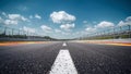 Empty asphalt racetrack stretching toward a bright horizon under a dramatic blue sky with scattered white clouds suggesting Royalty Free Stock Photo