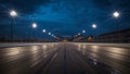 Empty asphalt racetrack stretching toward the illuminated starting structure under a dramatic dark blue twilight sky featuring Royalty Free Stock Photo