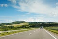 The empty asphalt road and blue sky with white clouds on the sunny day. Classic panorama view of road through fields