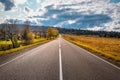 Empty asphalt road with cloudy sky and sunlight in autumn mountains Royalty Free Stock Photo