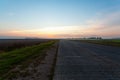 An empty asphalt road through the fields and forest in a thick fog at sunrise Royalty Free Stock Photo