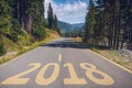 Empty asphalt road and New year 2018 concept. Driving on an empty road in the mountains to upcoming 2018 and leaving behind old 2 Royalty Free Stock Photo