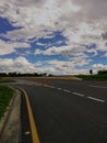 Empty asphalt road with sharp curve signs on blue cloudy sky Royalty Free Stock Photo