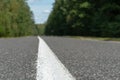 Empty asphalt road through woods and fields. New fresh asphalt pavement away from the city. Development of rural infrastructure. Royalty Free Stock Photo