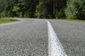 Empty asphalt road through woods and fields. New fresh asphalt pavement away from the city. Development of rural infrastructure. Royalty Free Stock Photo