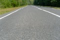 Empty asphalt road through woods and fields. New fresh asphalt pavement away from the city. Development of rural infrastructure. Royalty Free Stock Photo