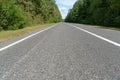 Empty asphalt road through woods and fields. New fresh asphalt pavement away from the city. Development of rural infrastructure. Royalty Free Stock Photo