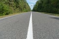 Empty asphalt road through woods and fields. New fresh asphalt pavement away from the city. Development of rural infrastructure. Royalty Free Stock Photo