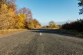 Empty autumn road along golden winter wheat fields at sunset Royalty Free Stock Photo