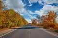 Empty autumn road, highway, with beautiful trees on the sides, against the background of a clear, blue sky Royalty Free Stock Photo