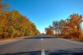 Empty autumn road, highway, with beautiful trees on the sides, against the background of a clear, blue sky Royalty Free Stock Photo