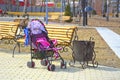 Empty baby carriage in the city park near the bench. Close to the trash can Royalty Free Stock Photo