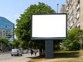 Empty banner on a city street with residential and office buildings and with green trees along the road. Blank billboard mockup