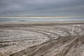 Empty baron secluded beach by the ocean with deep tire tracks in the soft sandy beach and dark storm clouds on the horizon Royalty Free Stock Photo