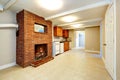 Empty basement room with brick fireplace