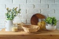 Empty basket on kitchen table with food jars and plants over white brick wall background. Kitchen mock up for design and product Royalty Free Stock Photo