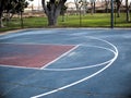 Empty basketball court lines painted on cement ground.