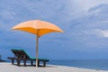 Empty beach chairs and orange umbrella from the sun against the cloudy sky. The Paradise place in Bali. Blue sea and