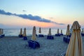 Empty beach early morning. Closed parasols and sunbeds stacked Royalty Free Stock Photo