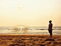 Empty beach with foot step marks. Lonely person staring at the sun.