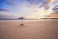 Empty beach with lonely umbrella at sunset