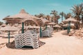 Empty beach with palm, white sunbeds, wicker umbrellas waiting for new summer holiday season tourists. Abandoned Royalty Free Stock Photo