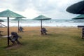 Empty beach on the seaside at the end of resort season with umbrellas and folded chairs in the cloudy day against the sea Royalty Free Stock Photo