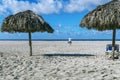 Empty beach, two beach umbrellas, a chaise longue, the figure of a man walking to the sea, traces of people in the sand,