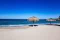 Empty beach with two palapas on sand, sea and the horizon in background against clear blue sky Royalty Free Stock Photo