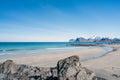 Empty beautiful beach during springtime on a sunny day with blue sky and silent ocean with small waves and ountainchain with snow