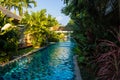 Empty, long swimming pool with fountain, surrounded by palm trees in the tropical jungle Royalty Free Stock Photo