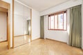 Empty bedroom with built-in wardrobe with trunk and folding mirror doors, red anodized aluminum window and curtains with sheers,