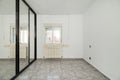 An empty bedroom with a custom built closet with black metal edged sliding mirror doors, a varnished sapele wood access door and