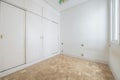 Empty bedroom with wall to wall white wooden Venetian style sliding door wardrobe and oak parquet slat flooring