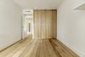 Empty bedroom with white shelves on the wall and custom-made built-in wardrobe with light oak wooden doors, air conditioning Royalty Free Stock Photo