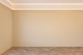 Empty beige interior with blank wall, mouldings, ceiling backlit and wooden chevron parquet floor.