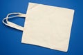 Empty beige textile bag on blue background, rejection of plastic bags