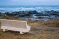 Empty bench on Atlantic Ocean coast in Portugal in the morning. Seascape in blue morning fog. Ocean beach with rocks. Royalty Free Stock Photo