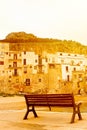 Empty bench captured on a vertical picture in bright orange sunset light. Taken on the coast of Sicilian city Cefalu, Italy.