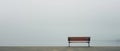 Empty bench in front of sea with foggy background