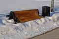 Empty bench and garbage bin in the snow