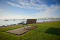 An empty bench on grass with blue sky and marina. Royalty Free Stock Photo