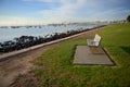 An empty bench on grass by the waters edge. Royalty Free Stock Photo