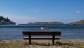 Empty bench at a sandy beach, moored boats, blue sea and sky background Royalty Free Stock Photo